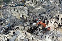 This aerial view shows residents, aided by heavy equipment, searching for victims and survivors amidst the rubble of collapsed buildings following an earthquake in the village of Besnia near the twon of Harim, in Syria's rebel-held noryhwestern Idlib province on the border with Turkey, on February 6, 2022. - Hundreds have been reportedly killed in north Syria after a 7.8-magnitude earthquake that originated in Turkey and was felt across neighbouring countries. (Photo by Omar HAJ KADOUR / AFP)