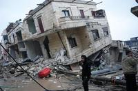 TOPSHOT - Residents stand in front of a collapsed building following an earthquake in the town of Jandaris, in the countryside of Syria's northwestern city of Afrin in the rebel-held part of Aleppo province, on February 6, 2023. - Hundreds have been reportedly killed in north Syria after a 7.8-magnitude earthquake that originated in Turkey and was felt across neighbouring countries. (Photo by Rami al SAYED / AFP)